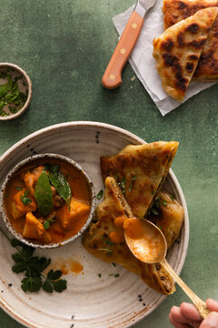 Murtabak drizzled with chicken curry on a green table