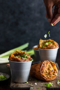 Cheddar scallion popovers in metal cups on rustic wooden board