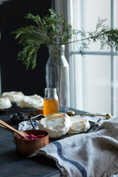 Mini pavlovas with berries and honey by a window