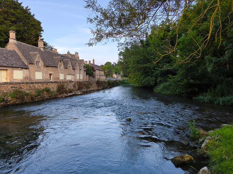The beautiful canal flowing riverside view of river coln with vibrant green trees in bibury