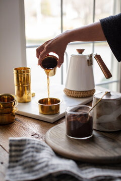 South Indian filter coffee being aerated into a brass tumbler