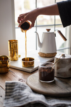South Indian filter coffee being aerated into a brass tumbler