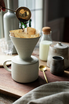 Ground coffee poured into filter cone on a wooden surface