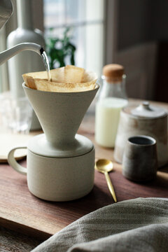 Boiling water  poured into coffee filter cone on a wooden surface