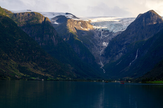 Scenic view of Briksdalsbreen glacier tongue melting into Oldevatnet lake in a steep mountain valley, Norway