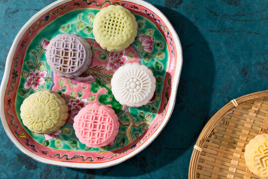 Colorful patterned mooncakes arranged on floral plate and bamboo tray