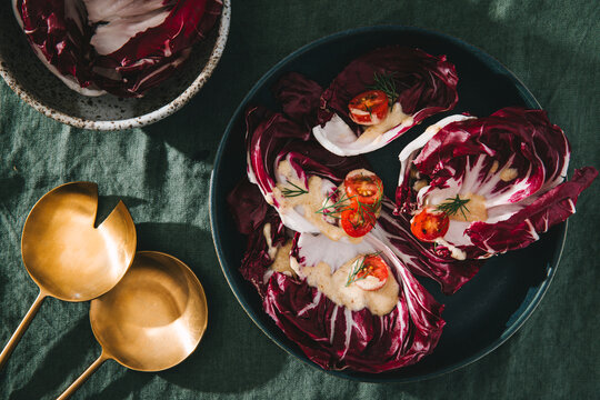 Radicchio leaves topped with dressing, tomatoes, and dill