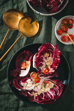 Radicchio leaves topped with dressing, tomatoes, almonds, and dill