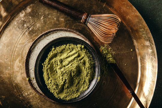 Matcha powder with bamboo whisk on brass tray
