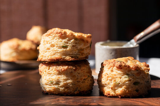 Macro Shot of Golden cheddar scallion biscuits on rustic wooden board