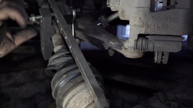 Car mechanic repairing vehicle suspension close up. Car mechanic removing the drive shaft and CV joint from a vehicle.
