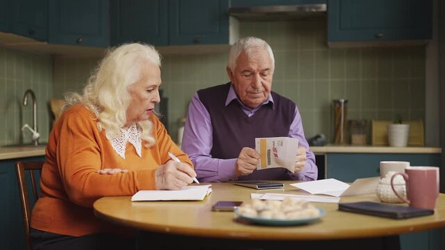 Senior couple calculating expenses and reading overdue bills, budget planning
