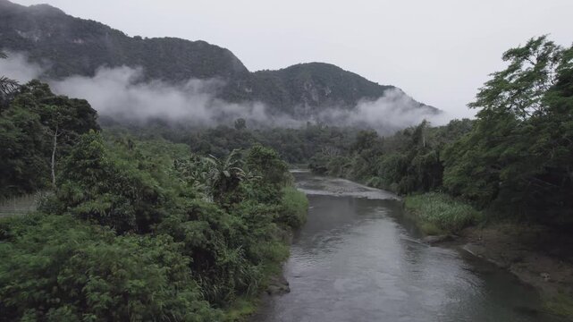 Exploring a Calm River Valley Surrounded by Misty Mountains in Lush Greenery