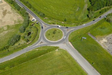 Fototapeta premium Top down aerial drone view of a landscaped roundabout near Wetherby Racecourse in Leeds West Yorkshire UK surrounded by roads grass and countryside during springtime