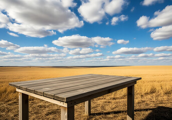Fototapeta premium Empty wooden table in a golden field under a cloudy blue sky