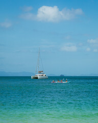 Fototapeta premium White Catamaran and People in Kayak on Turquoise Tropical Ocean
