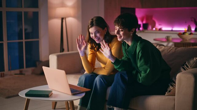 Smiling sisters waving webcam laptop starting virtual conference evening home.