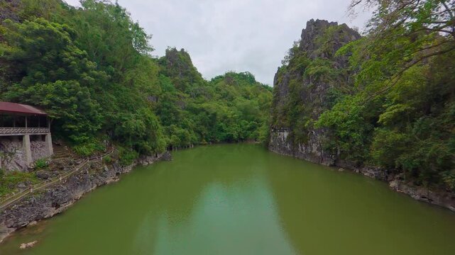 Slow Panning Shot of Danau Limbong Natural Lake with Emerald Green Water Enclosed by Towering Limestone Karst Cliffs and Lush Forest in Tana Toraja Sulawesi Indonesia 4K Footage