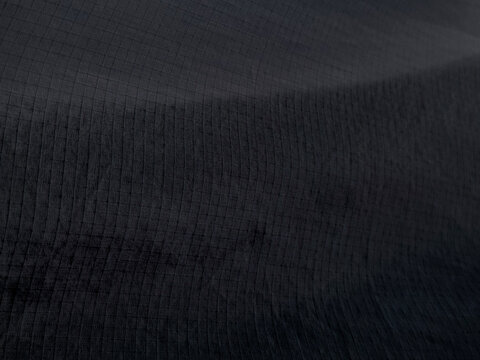 Black Ripstop Fabric Texture Close Up, Dark Synthetic Waterproof Nylon Material Background with Grid Pattern, Durable Technical Textile for Outdoor Gear and Sportswear Apparel.