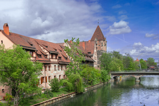 Historic Schuldturm tower on Pegnitz river embankment in Nuremberg, Germany viewed from bridge. Outside view, medieval style