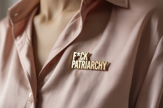 Gold pin reading FCK patriarchy on pink blouse. Bold feminist statement against gender inequality and systemic oppression. Generative ai, AI generated