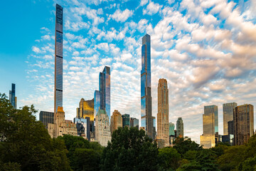 The tall and thin residential skyscrapers of Billionaires Row rise above the green trees of Central...
