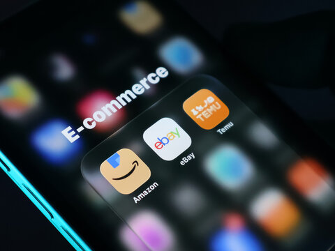Closeup of a smartphone screen showing popular ecommerce mobile applications including amazon, ebay, and temu icons on a digital folder