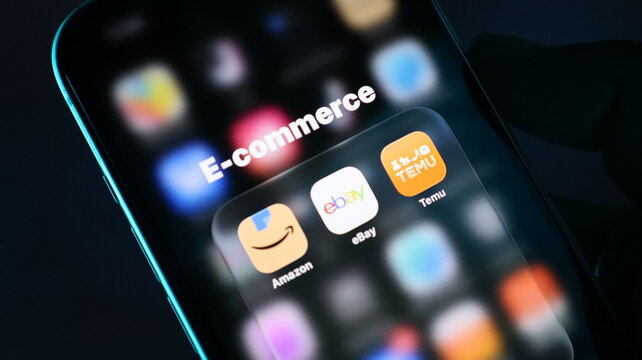 Closeup of a smartphone screen displaying popular ecommerce shopping apps including amazon, ebay, and temu on a dark background