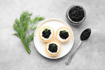 Naklejka premium Tasty tartlets with black caviar, cream cheese and dill on light grey table, flat lay