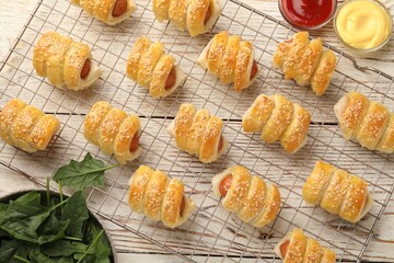 Obraz premium Puff pastry. Tasty sausages in dough and sauces on white wooden table, flat lay