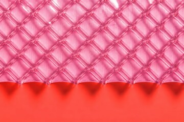 Obraz premium Pink quilted textile texture with diamond pattern over red background in soft abstract close up
