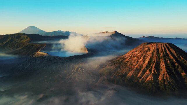 Cinematic aerial view of Mount Bromo volcano at sunrise &ndash; Breathtaking drone shot of morning mist covering the vast caldera and dramatic mountain peaks in East Java, Indonesia landscape 4k
