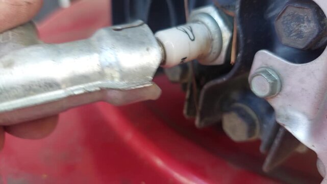 Mechanic hand connecting a spark plug wire cap on a lawn mower engine.