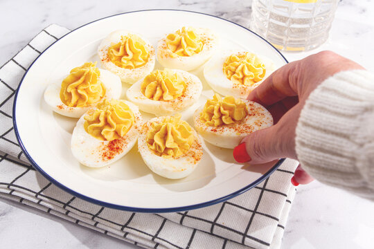stuffed eggs with paprika, on a plate, a woman's hand reaches for it,