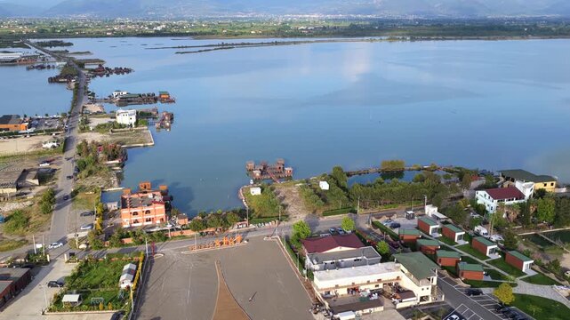 Aerial video capturing waterfront stilt structures, a causeway road along the Patok Lagoon in Albania. 