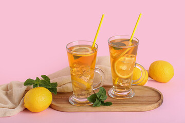 Fototapeta premium Glass cups of lemon ice tea with mint and citrus fruits on pink background