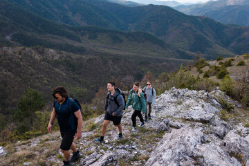 Fototapeta premium Group of friends hiking together along a rocky mountain trail enjoying outdoor adventure, camaraderie and panoramic mountain views