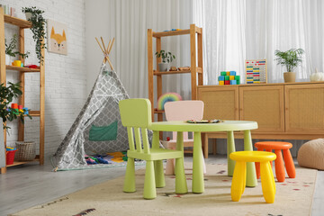 Interior of stylish playroom with table, play tent and toys in kindergarten © Pixel-Shot