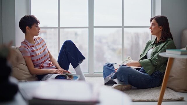 Girls enjoy relaxed conversation sitting home floor. Calm two women talking