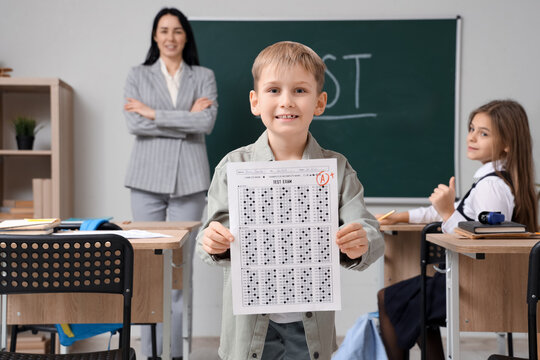 Cute schoolboy with results of test in classroom
