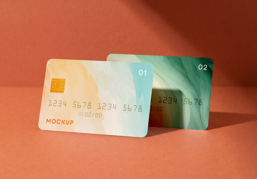 Two credit cards mockup set with abstract watercolor and texture design standing on a terracotta background with soft shadows