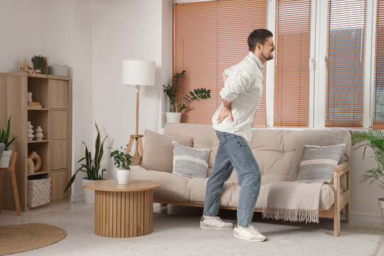 Young man suffering from back pain at home
