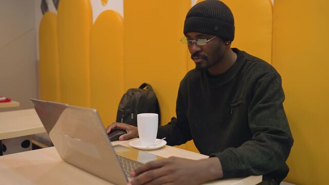 Focused work environment. Person engaged with computer at vibrant coworking location early morning. Concentrated professional working on laptop within warm and inviting shared office setting