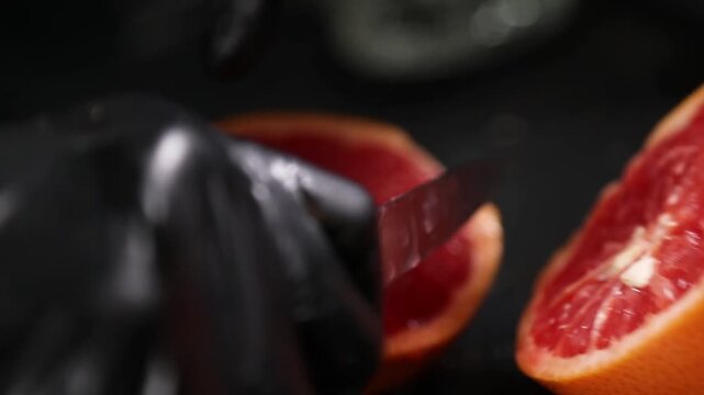 Chef cortando una naranja fresca con un cuchillo sobre una encimera negra. Chef profesional cortando una naranja fresca con un cuchillo. Preparaci&oacute;n culinaria artesanal, ingrediente c&iacute;trico gourmet.