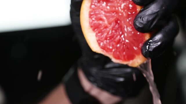Chef exprimiendo naranja fresca a mano. Un chef profesional exprime una naranja fresca con la mano desnuda. T&eacute;cnica de c&iacute;tricos crudos, extracci&oacute;n artesanal de jugo natural.