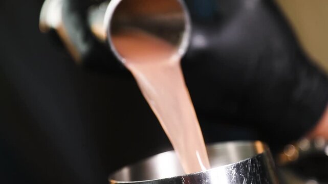 Barman colando l&iacute;quido con colador met&aacute;lico sobre fondo negro. Barman profesional filtrando un c&oacute;ctel con un colador met&aacute;lico. C&oacute;ctel artesanal, t&eacute;cnica de bar precisa, servicio de primera.