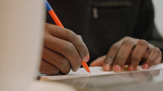 Closeup hands sketching orange pen on table creative designer drafting layout beside laptop, focused studio mood, detailed line work, quick concept notes and visual exploration.