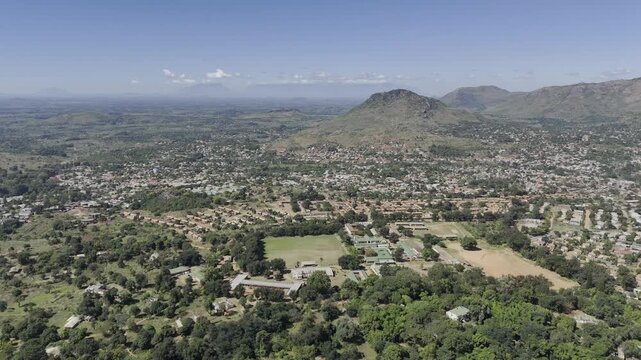 Drone flies over flat city on a sunny day in Zomba, Malawi