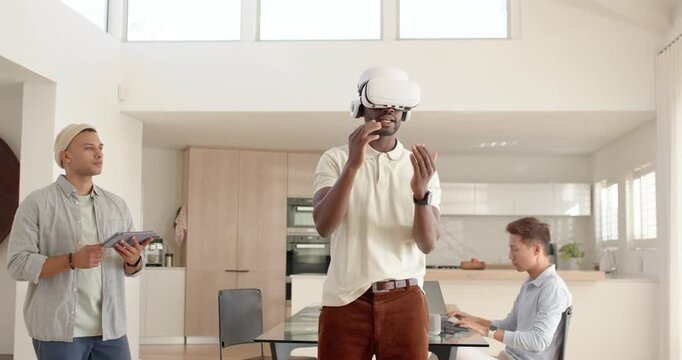 Diverse team demo starting at home, VR user tuning headset, gesturing, noting tablet, typing laptop