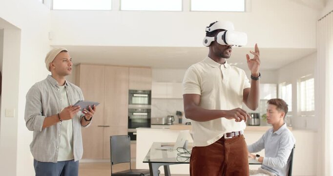 Diverse team testing VR demo on start in loft kitchen headset user gesturing tech checking laptop